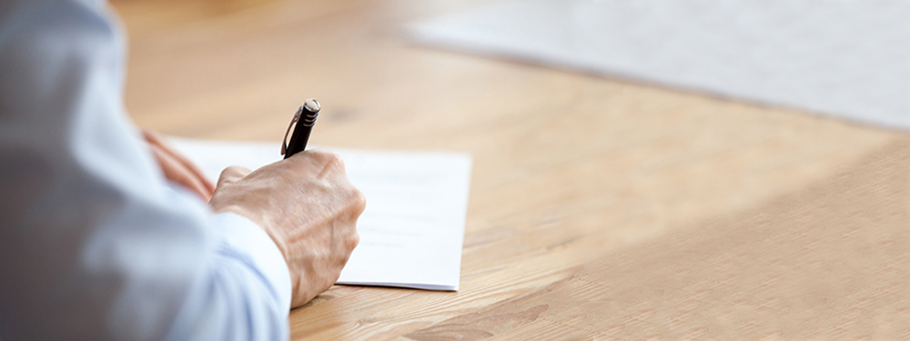 Arm and pen writing on desk